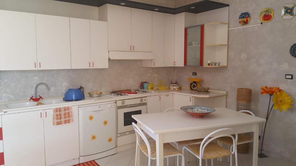 a kitchen with white cabinets and a table with a bowl on it at A due passi dal mare in Ribera
