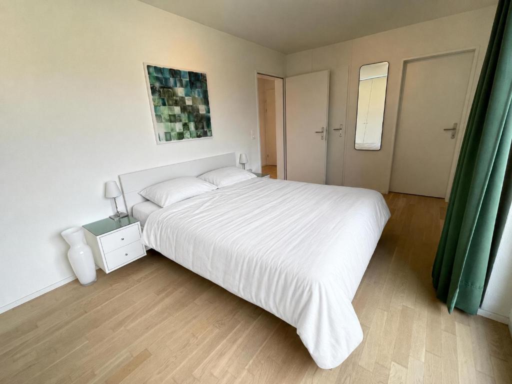 a bedroom with a large white bed with a night stand at Brüttisellen, Lindenbuck in Brüttisellen
