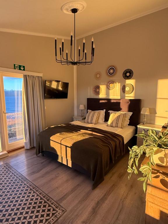 a bedroom with a large bed and a chandelier at Mörk Superior Cottages in Hvammstangi