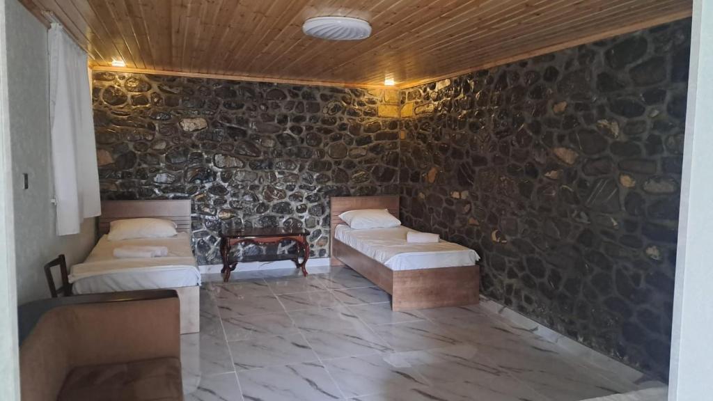 a room with two beds in a stone wall at Old Rooms in Sheki