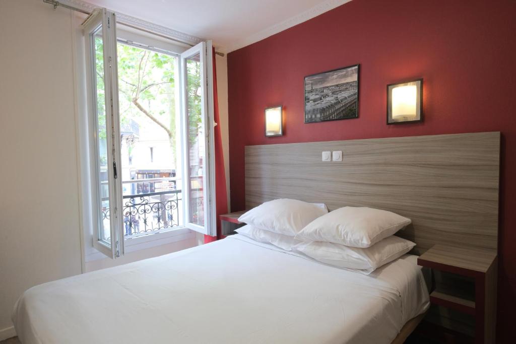a bedroom with a large white bed with a window at Hipotel Paris Gambetta République in Paris