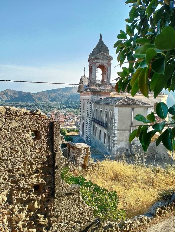 an old building with a clock tower on a hill at Flavia's House in Gaggi
