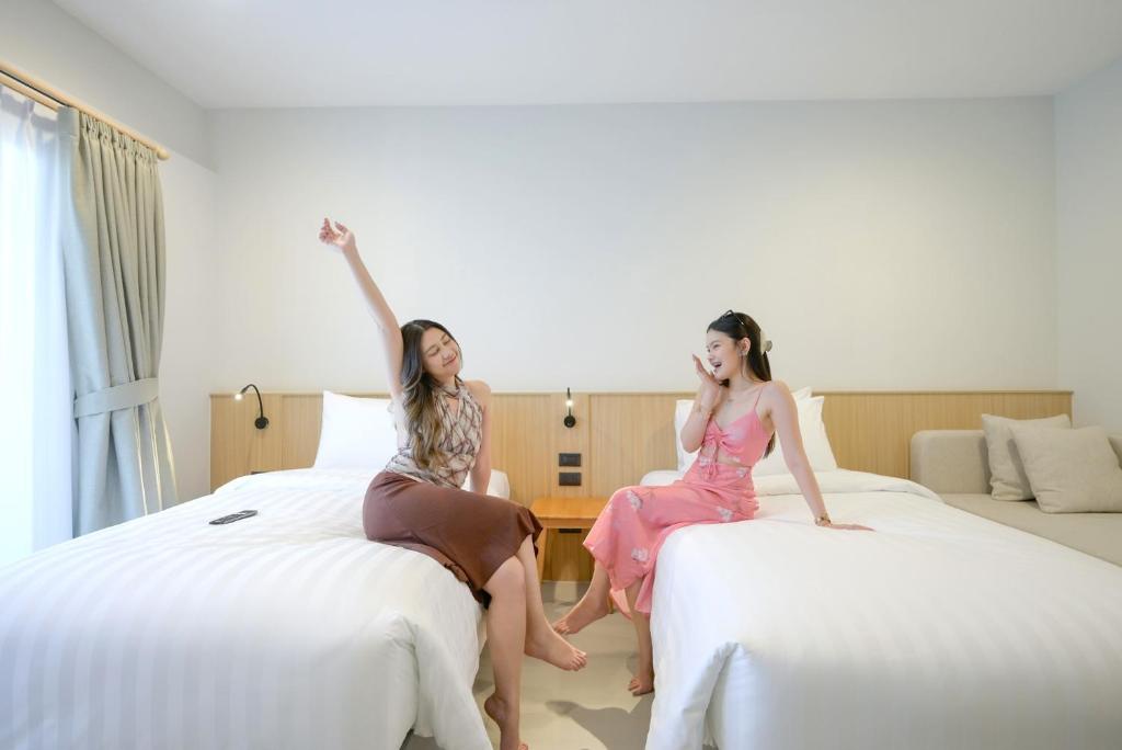 two women sitting on beds in a hotel room at Manditel North Pattaya in North Pattaya