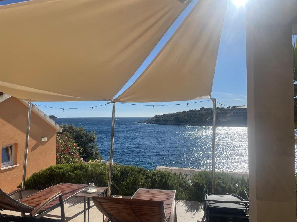 a view of the ocean from a patio with chairs and an umbrella at Apartment Tranquillo in Vela Luka