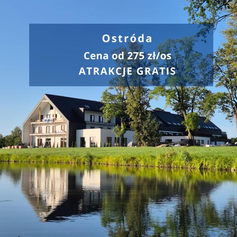 ein Haus neben einem See mit den Worten Ontario Canario Z Pros in der Unterkunft Natural Hotel przy plaży-Ostróda-basen na III kondygnacji in Ostróda