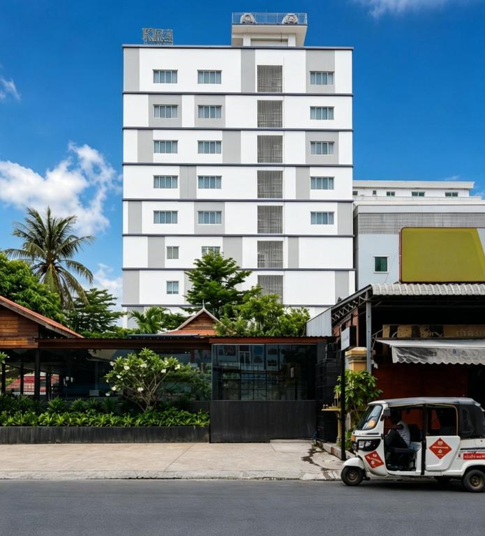 Ein kleiner Wagen parkte vor einem hohen Gebäude in der Unterkunft KIRA Hotel in Phnom Penh