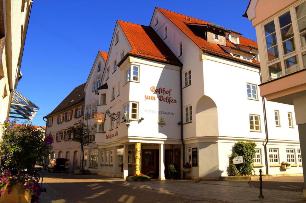 ein weißes Gebäude mit rotem Dach auf einer Straße in der Unterkunft Hotel zum Ochsen in Ehingen