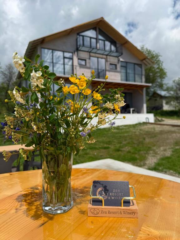 a vase of flowers on a table in front of a house at Zen Resort and Winery in Slănic