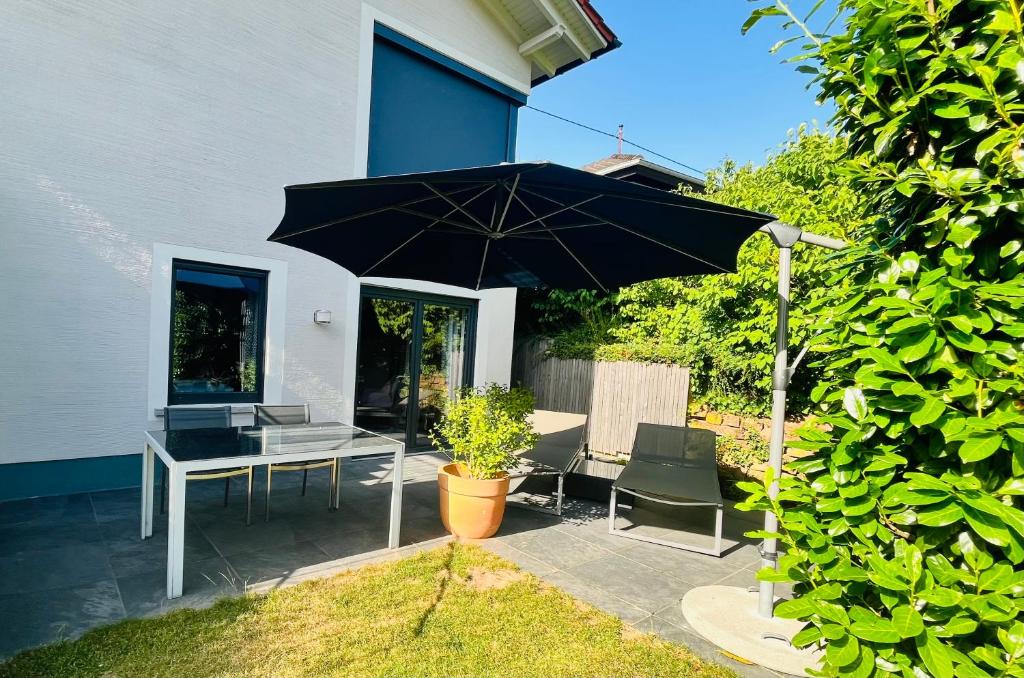 a patio with a black umbrella and a table and chairs at Bonne âme - Ferienwohnung mit Sauna in Sankt Martin