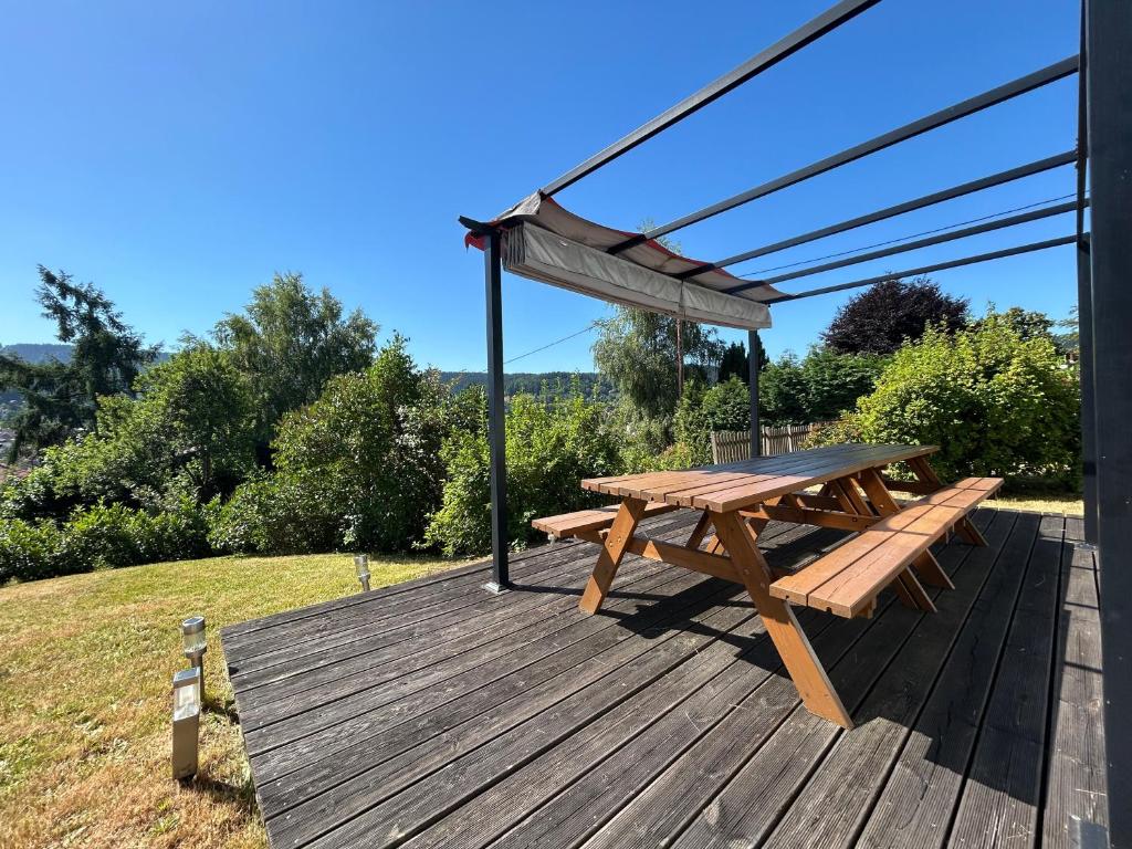 a picnic table and a canopy on a deck at Appartement RDC Chalet à 300m du lac de Gérardmer in Gérardmer