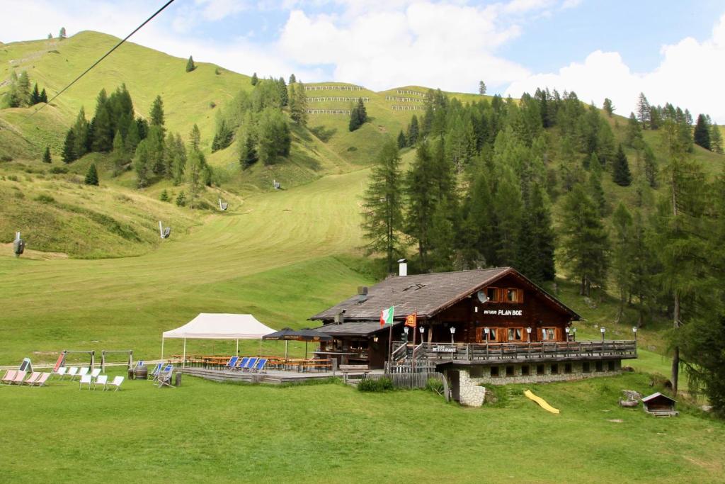 a building in the middle of a field with a mountain at Rifugio Plan Boè in Livinallongo del Col di Lana