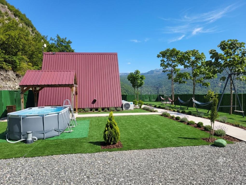 a yard with a red building and a swimming pool at Cottage Harmony in Racha-კოტეჯი ჰარმონია რაჭაში in Ambrolauri