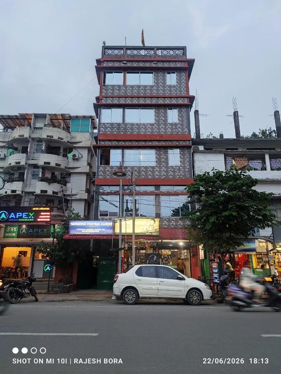 a white car parked in front of a tall building at SH Homestay in Tezpur