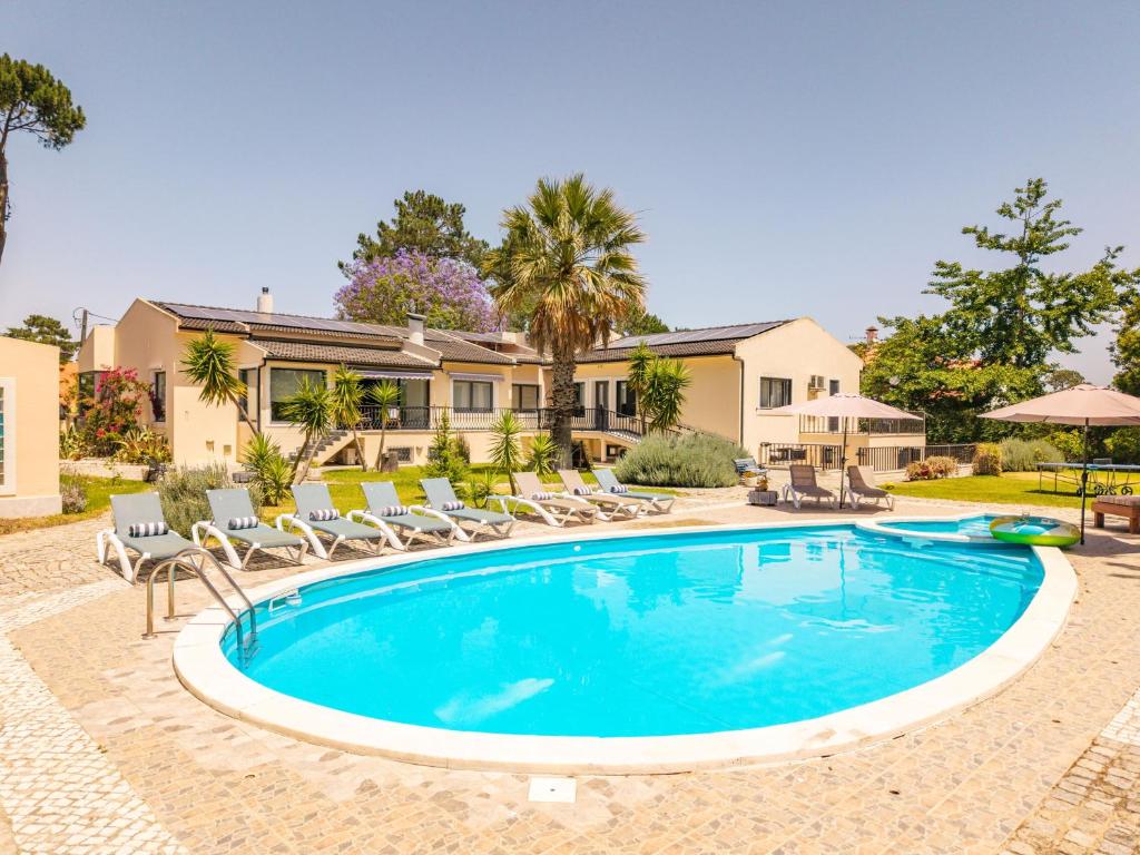 a swimming pool with chairs and a house at Villa Praia e Floresta in Aroeira
