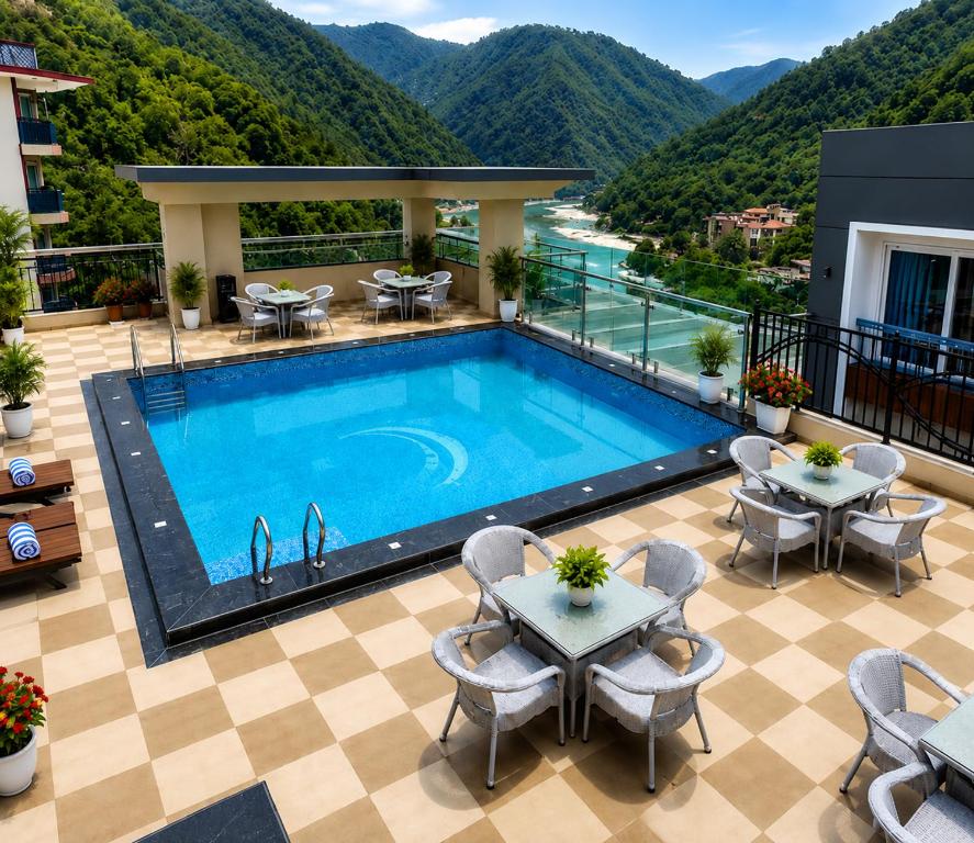 a pool on the roof of a building with tables and chairs at Foxoso Heights, Tapovan in Rishīkesh