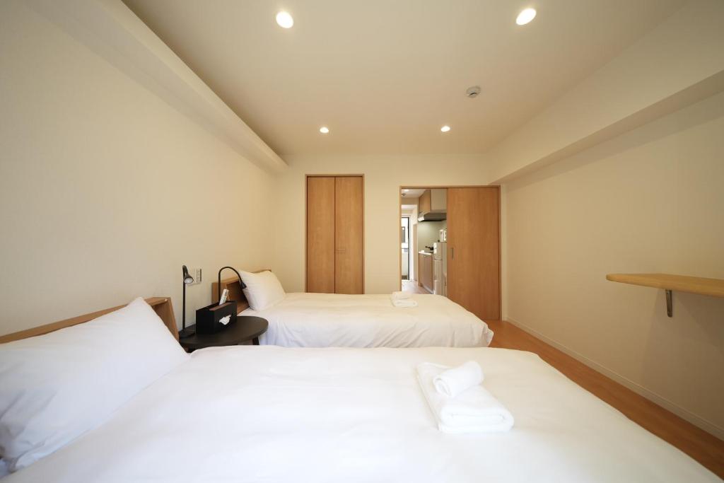 a hotel room with two beds with white sheets at Hotel Otsukahouse in Tokyo