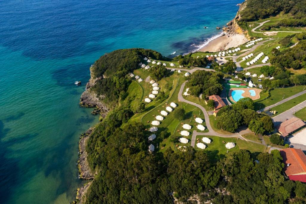 an aerial view of a golf course on a hill next to the ocean at Kampaoh Las Arenas in Pechón