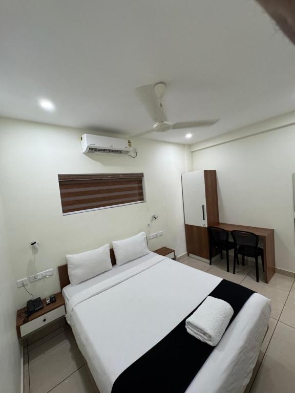 a bedroom with a large white bed and a desk at Regal residency in Perintalmanna