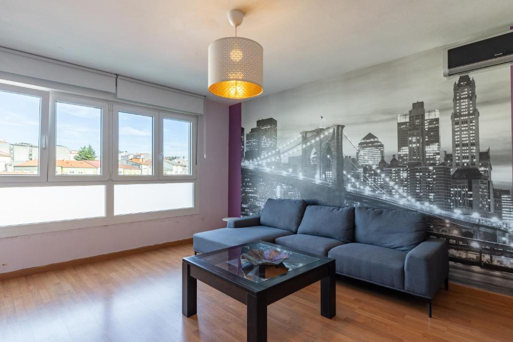 a living room with a blue couch and a city mural at Apartamento familiar acogedor in Ordes
