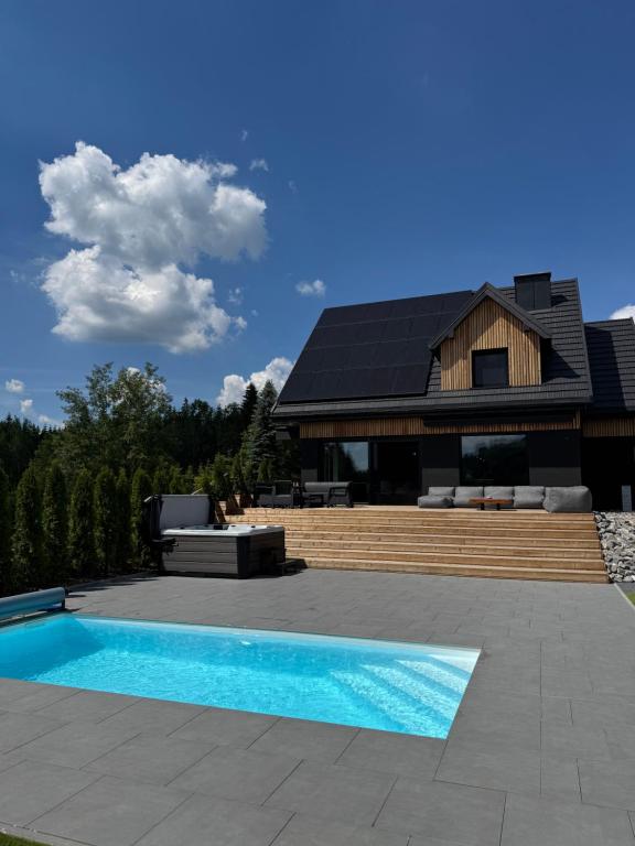 a house with a swimming pool in front of a house at Willa Black Wood in Istebna