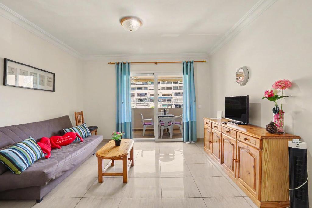 a living room with a couch and a tv at Los Cristianos Plaza Centre suite in Los Cristianos