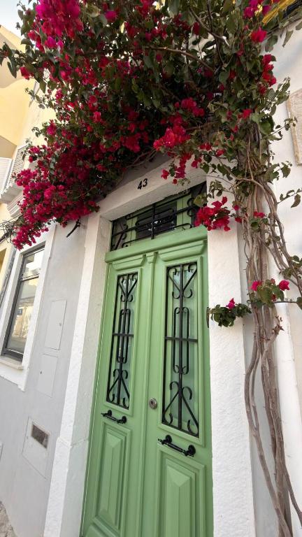 a green door on a white building with pink flowers at Casa Melro in Faro