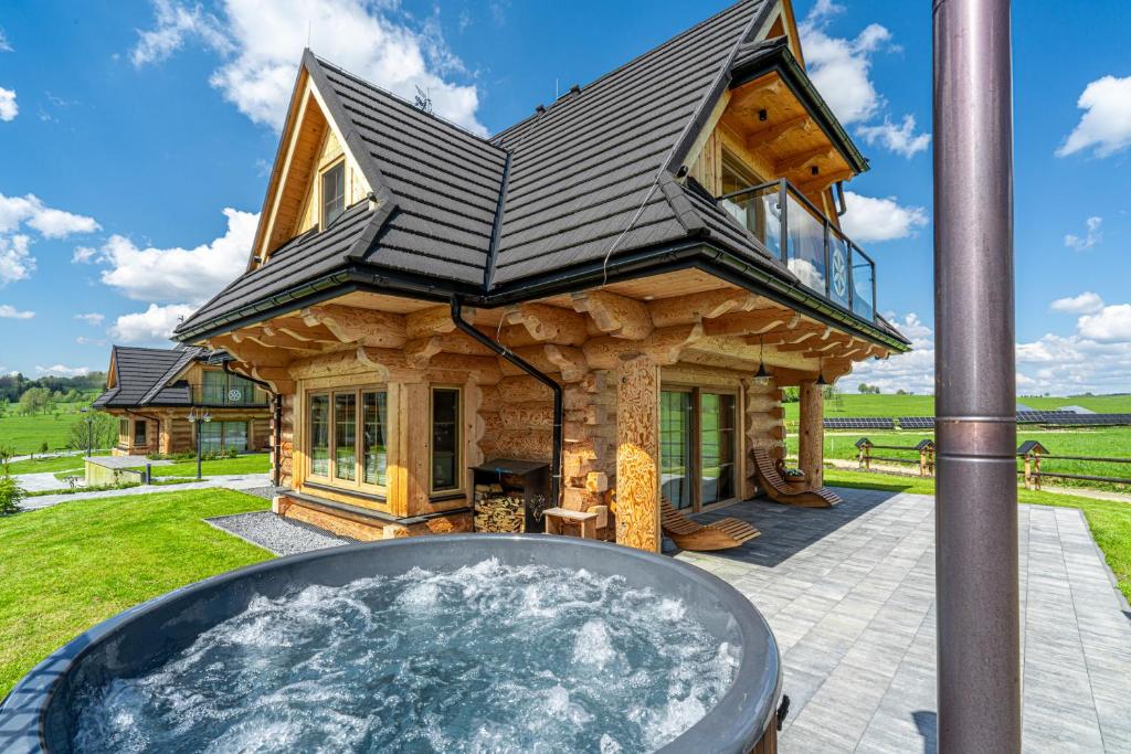 a log home with a hot tub in the yard at Jagodowa Osada - domki z balią z hydromasażem blisko term in Dzianisz