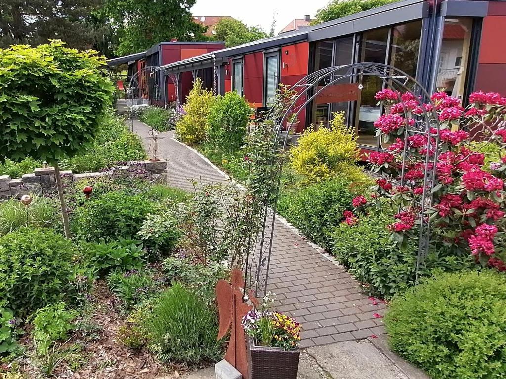 a garden with colorful flowers and a brick path at HOTEL SPATZENNEST Vogelsberg in Herbstein