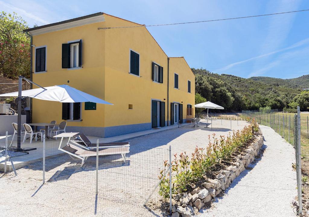 a yellow house with a table and chairs and an umbrella at Sansone Sul Mare Appartamenti in Portoferraio