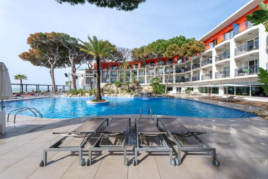 a hotel with a swimming pool with chairs in front of a building at Estival Centurión Playa in Cambrils