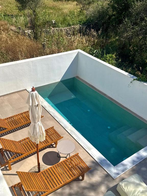 ein Schwimmbecken mit zwei Stühlen und einem Tisch in der Unterkunft Merichas Luxurious Villa in Kythnos