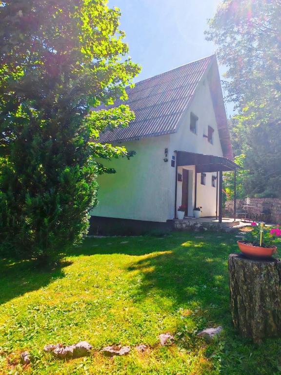 a white house with a tree and a yard at Kuća za odmor Iva in Lič