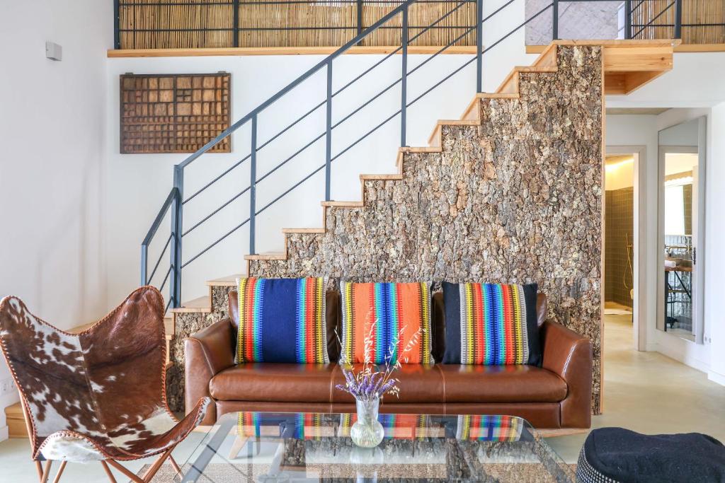 a living room with a brown couch and stairs at Vale das Estrelas in São Teotónio