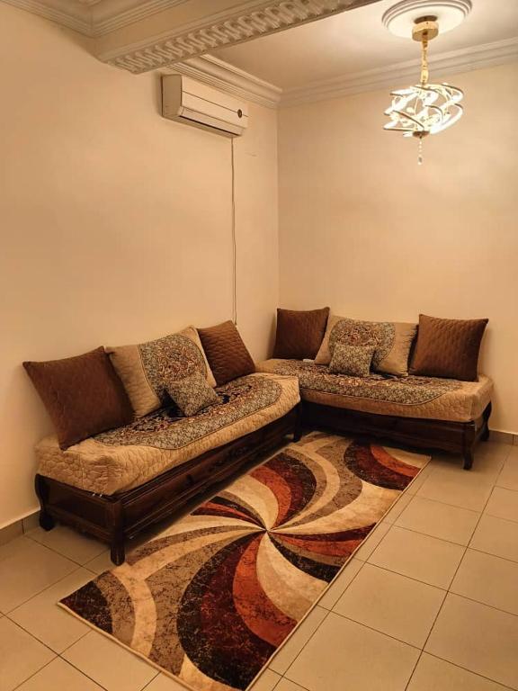 a living room with two couches and a rug at Skikda in Cité el ʼArbi Ben Mhîdi