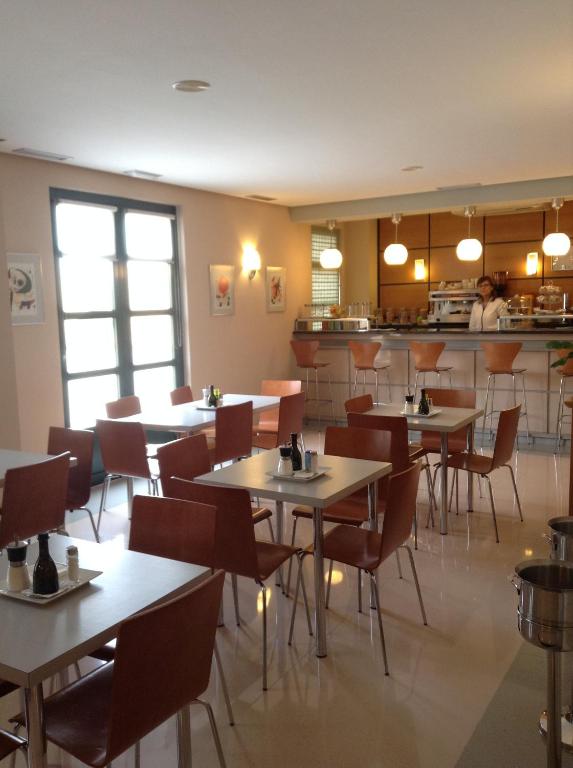 a restaurant with tables and chairs and a kitchen at Hotel Central in Valdepeñas