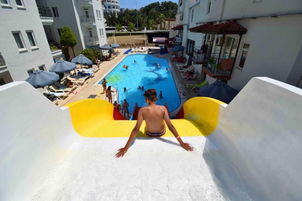 a man sitting on a slide at a swimming pool at Blue Garden Family Side in Side