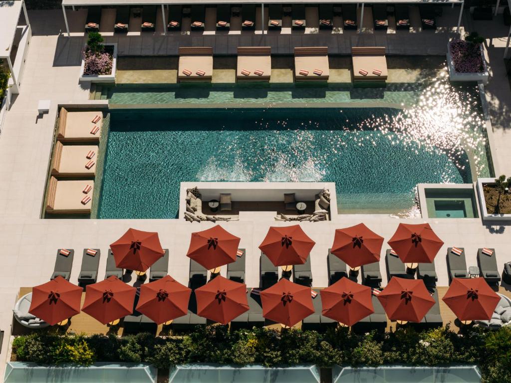 an overhead view of a swimming pool with red umbrellas at Santorini Heart Hotel & Spa in Fira