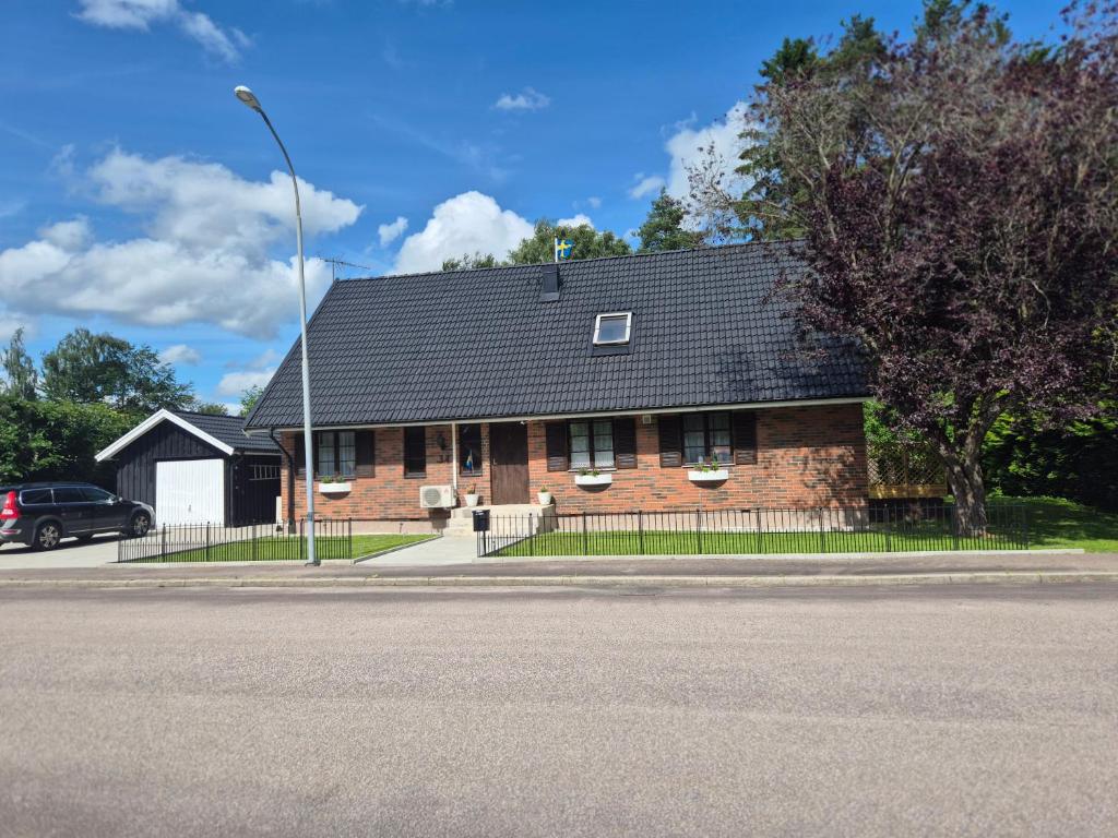 a brick house with a black roof on a street at Stenberg Nature Residence in Tyringe
