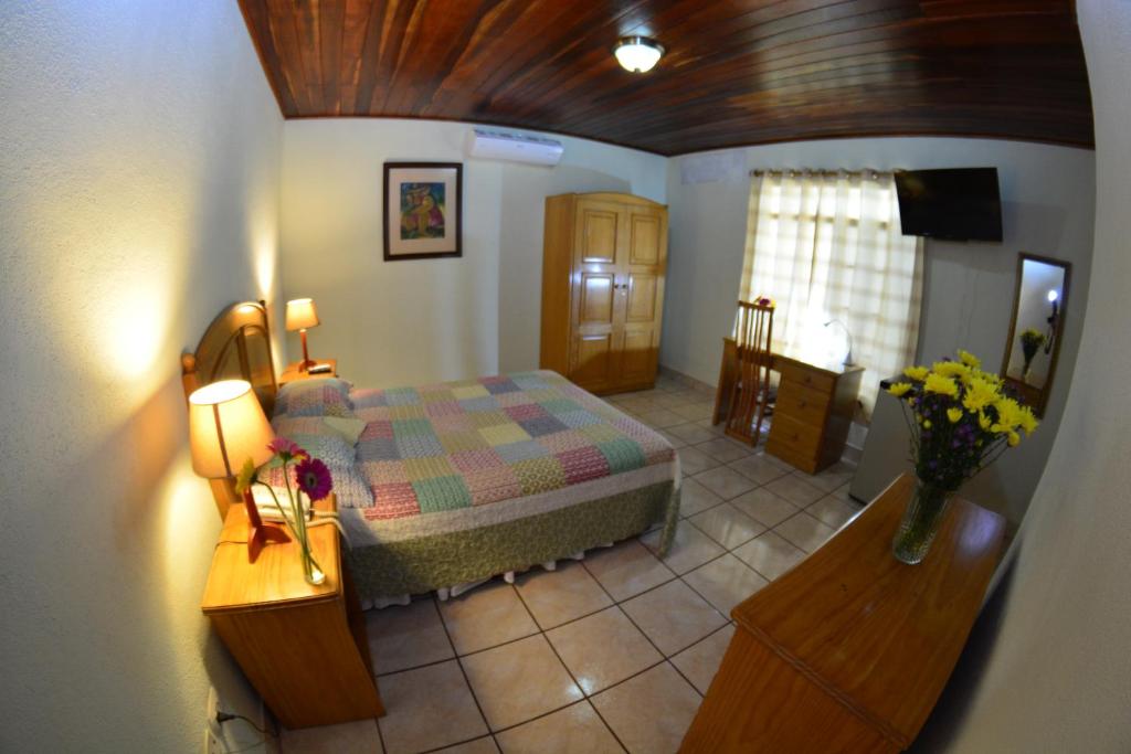 Hotel Posada Don Pantaleon في ماناغوا: غرفة نوم بسرير وطاولة مع ورد