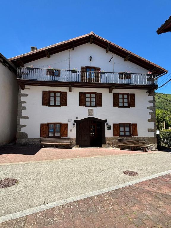 a large white building with a balcony on top at La Posada Nueva in Viscarret-Guerendiáin