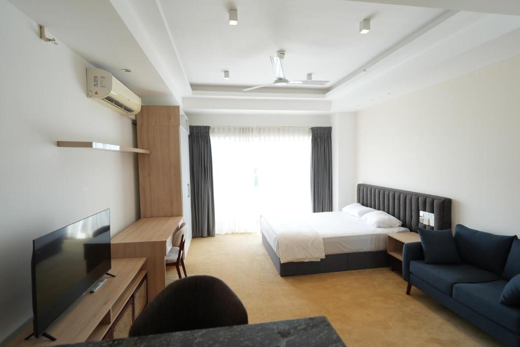 a room with a bed and a couch and a tv at Ceylon Vacation - Negombo in Negombo