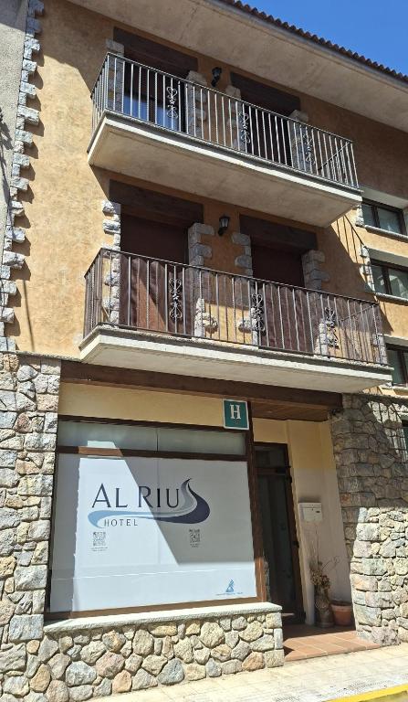 an apartment building with a balcony and a sign in a window at Hotel Al Riu in Bagá