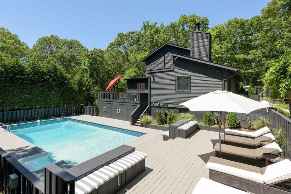 a house with a swimming pool and a patio with an umbrella at Villa Sapphire Bay in Sag Harbor