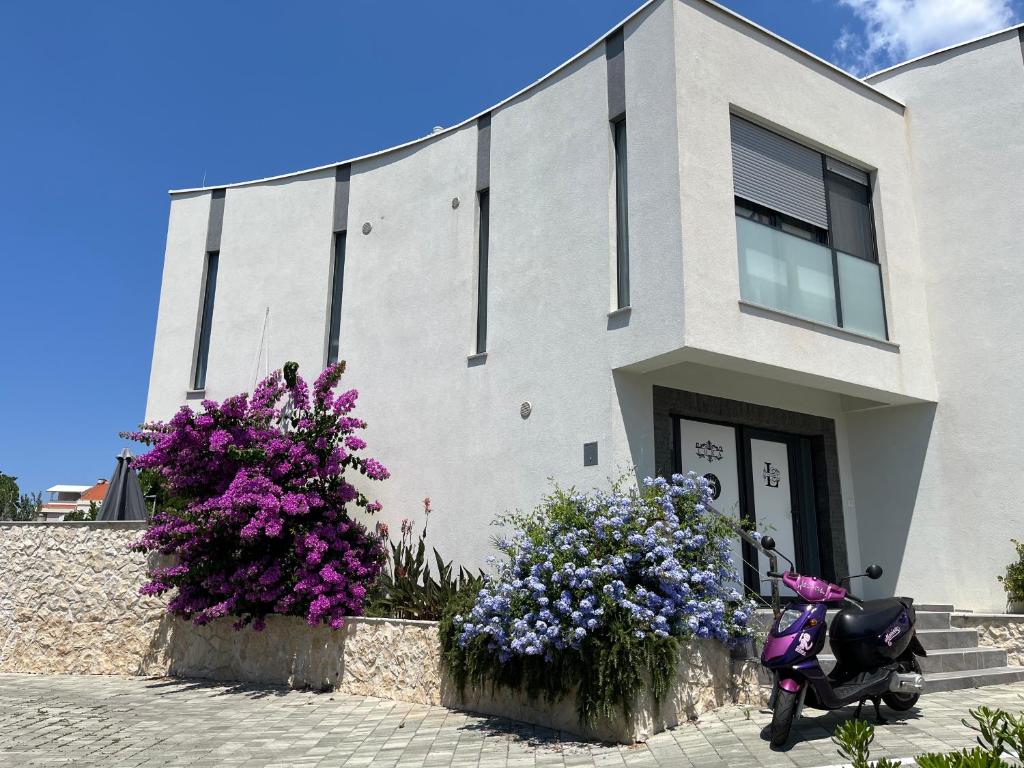 a motorcycle parked in front of a building with flowers at Legacy apartment 1 with privat jacuzzi and apartment 2 with BBQ in Novalja