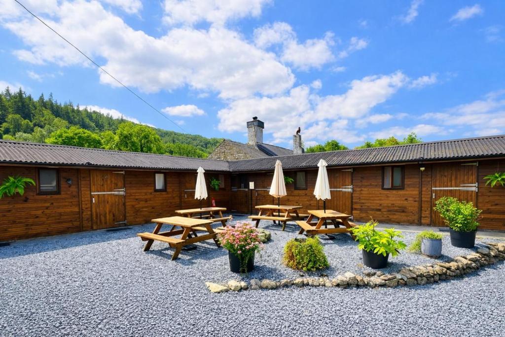a patio with picnic tables and umbrellas in front of a building at Private Heated Bedrooms at The Bunkhouse in Snowdonia Perfect for Bikers and Walkers in Dolgellau