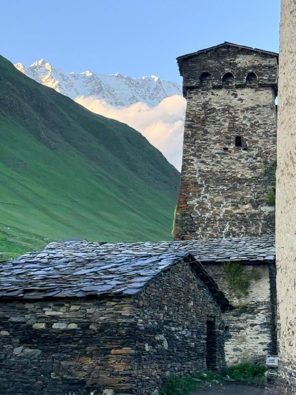 an old stone building with a mountain in the background at Nizharadze's Tower in Ushguli