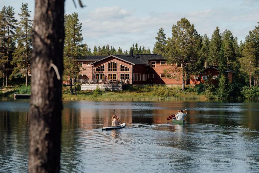 a couple of people in the water in front of a house at Pinetree Lodge in Kangos