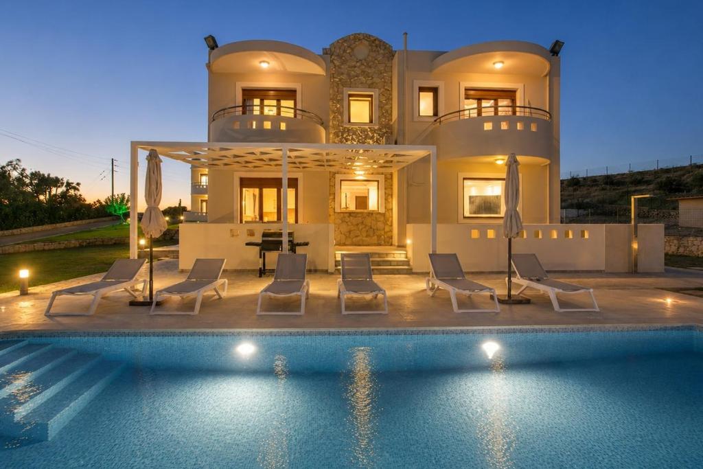 a villa with a swimming pool in front of a house at Villa Kallithea Sunrise in Koskinou
