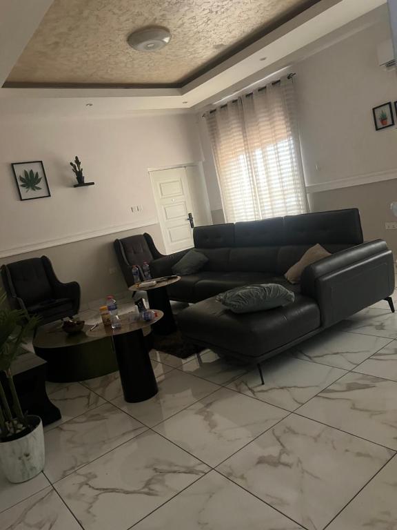 a living room with a black leather couch and tables at EL and LOUNGE in Accra