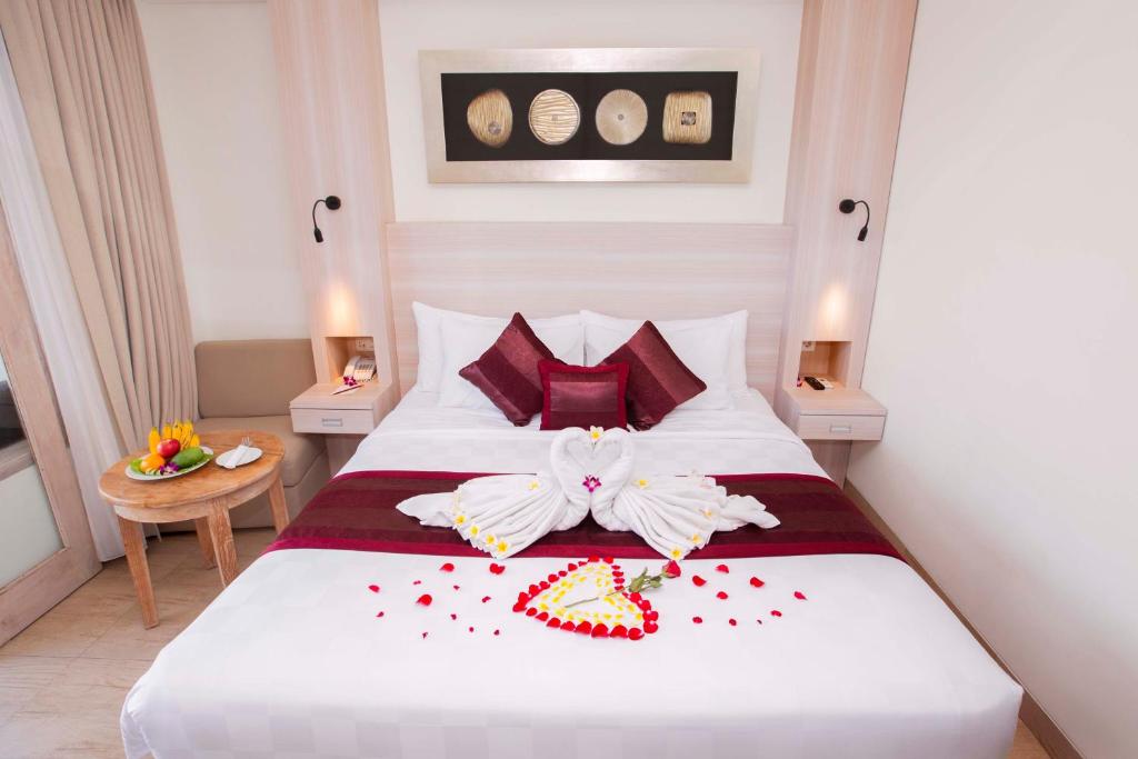 a bedroom with a large white bed with red pillows at Core Hotel Benoa in Nusa Dua